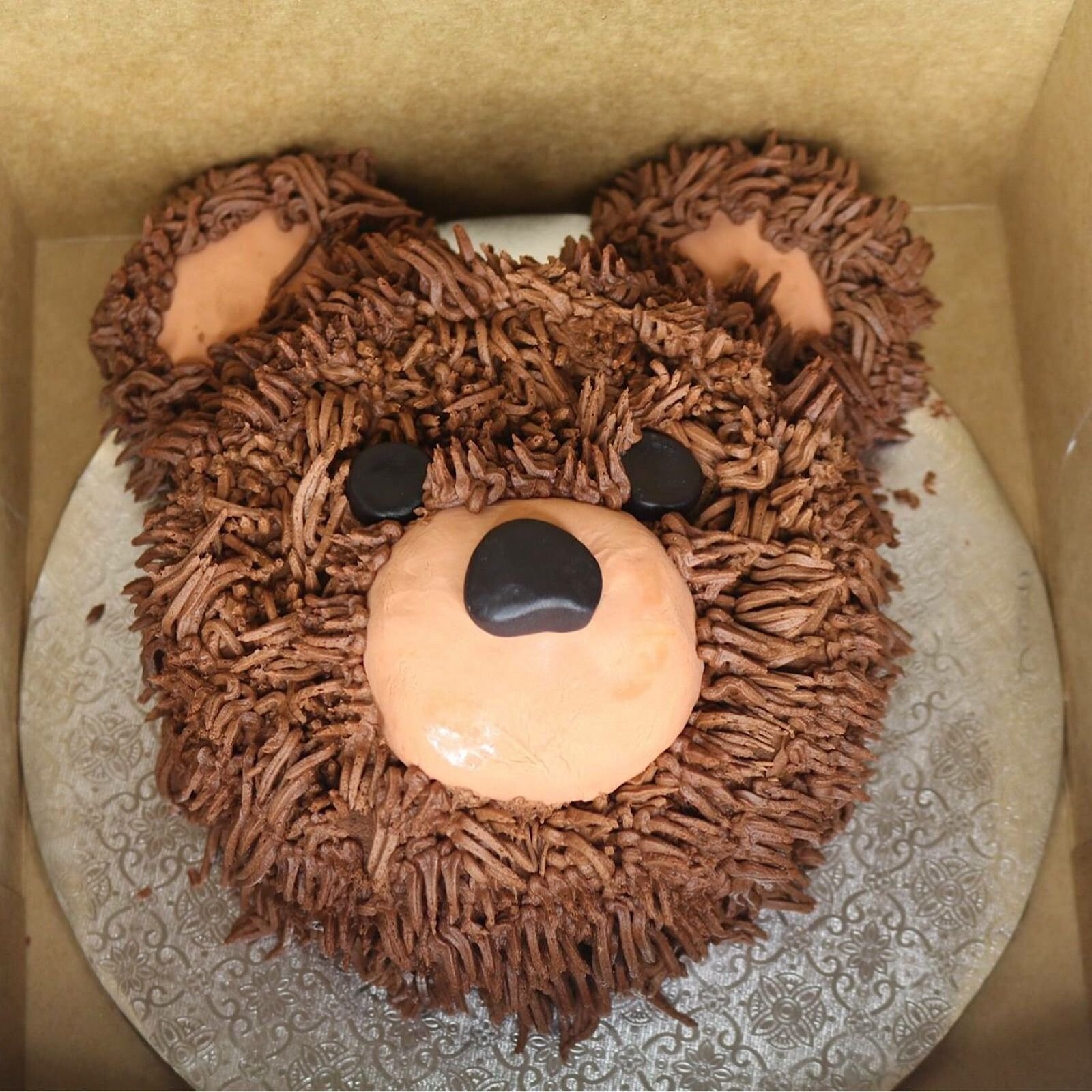 A teddy bear chocolate cake with brown color icing.