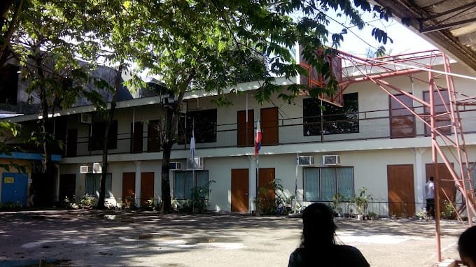 Shekinah Glory Christian Academy building featuring a basketball court and a tree in the foreground.