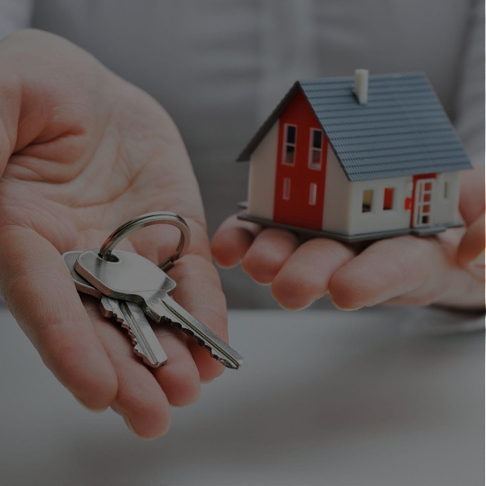 A person holding keys and a house model. Ideal for property management