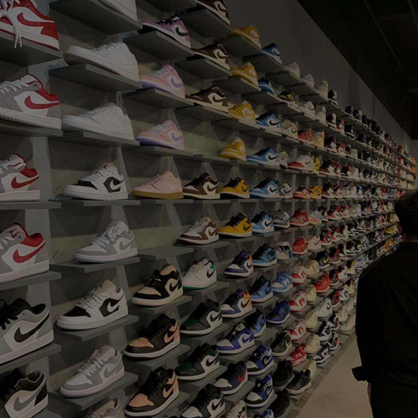 A man examining a wall of sneakers in a store