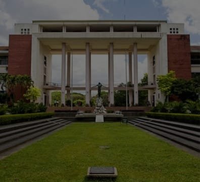 A statue stands in front of a school building with columns