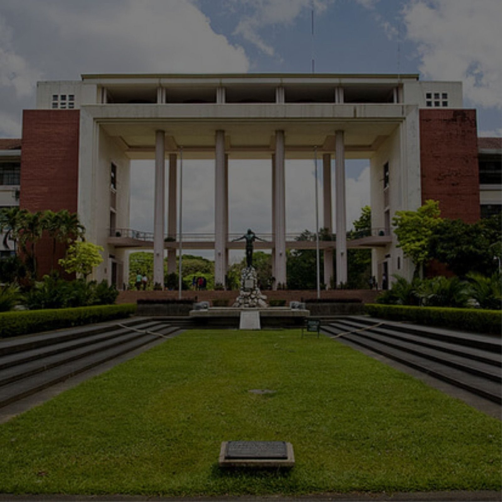 A statue stands in front of a school building with columns