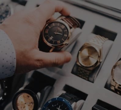 A person showcasing a watch in front of a variety of watches at a watch store