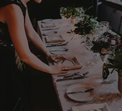 A wedding planner setting a table with a white tablecloth for a special occasion