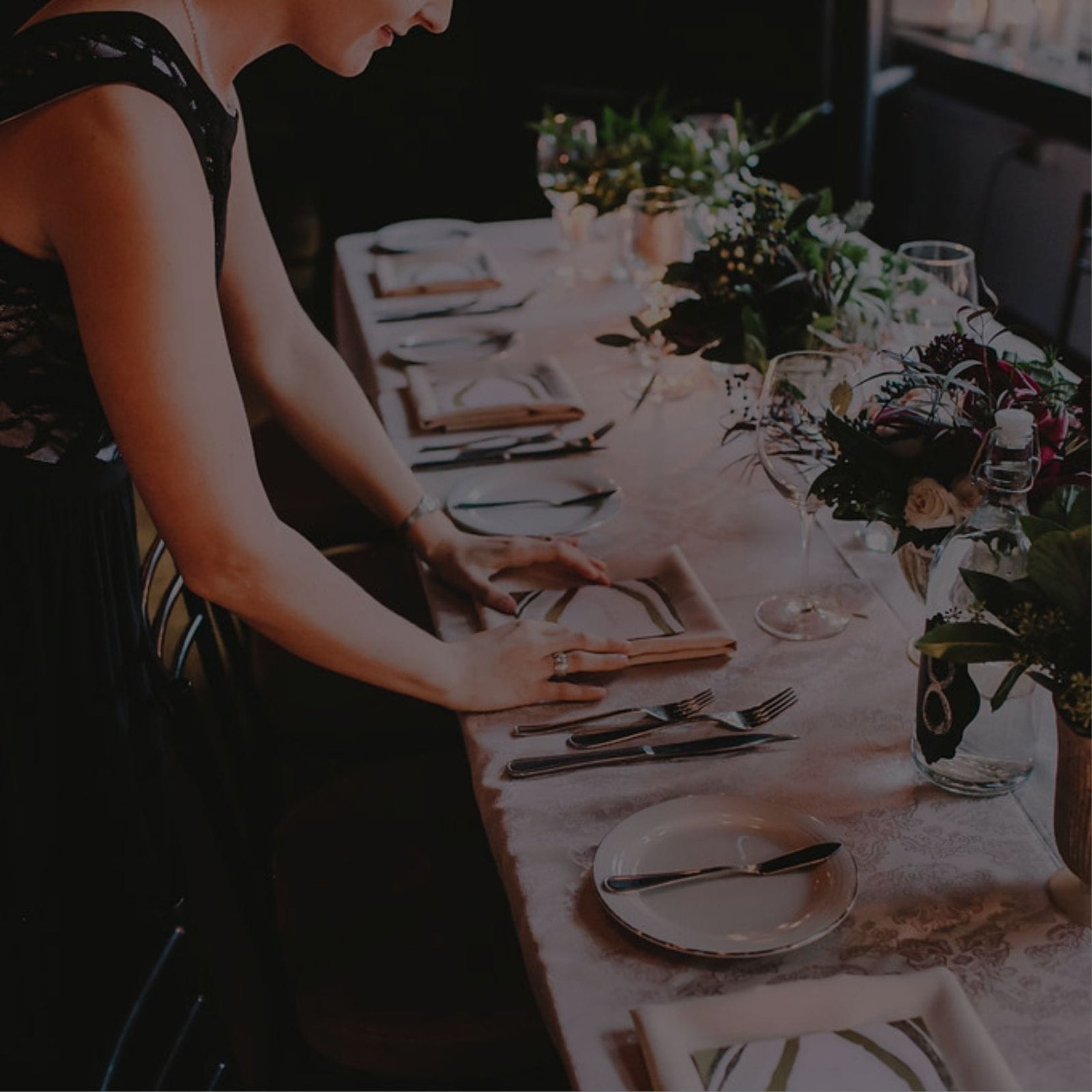 A wedding planner setting a table with a white tablecloth for a special occasion