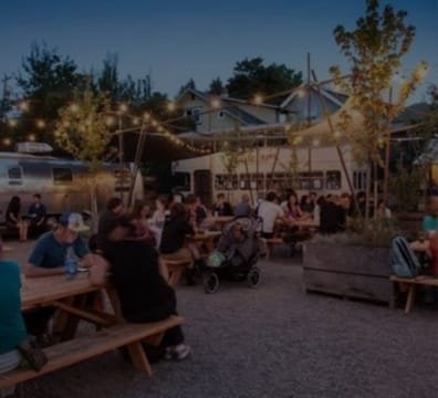 People sitting at tables at night in an outdoor area, enjoying their time together.