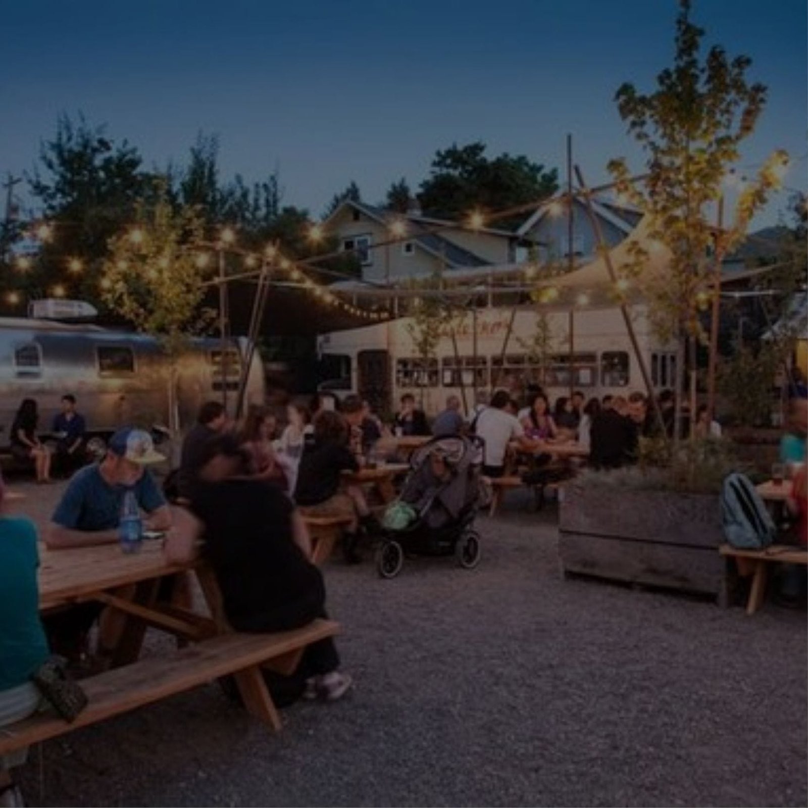 People sitting at tables at night in an outdoor area, enjoying their time together.