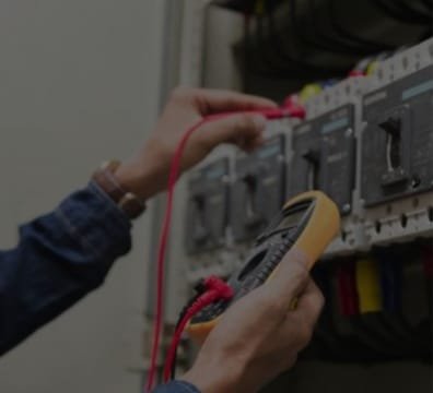 Multimeter in hand, an electrician examines an electrical panel