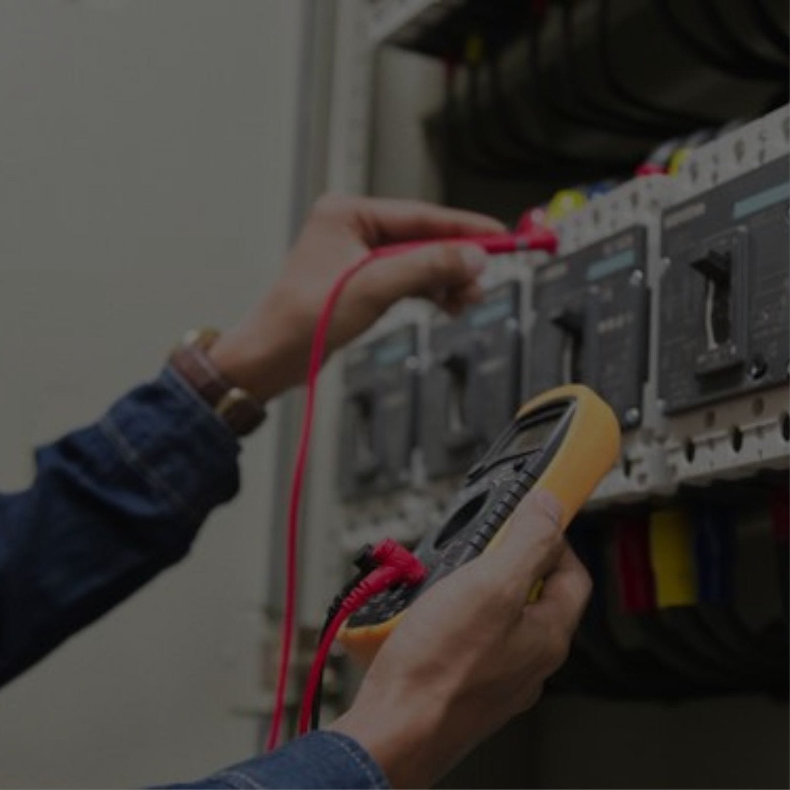 Multimeter in hand, an electrician examines an electrical panel