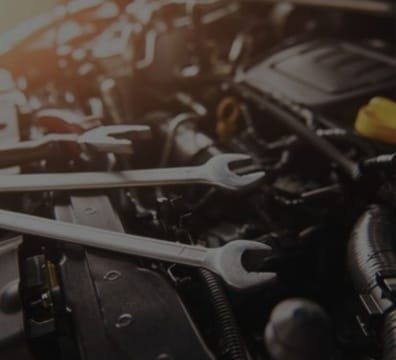 A close-up of a car engine with wrenches nearby