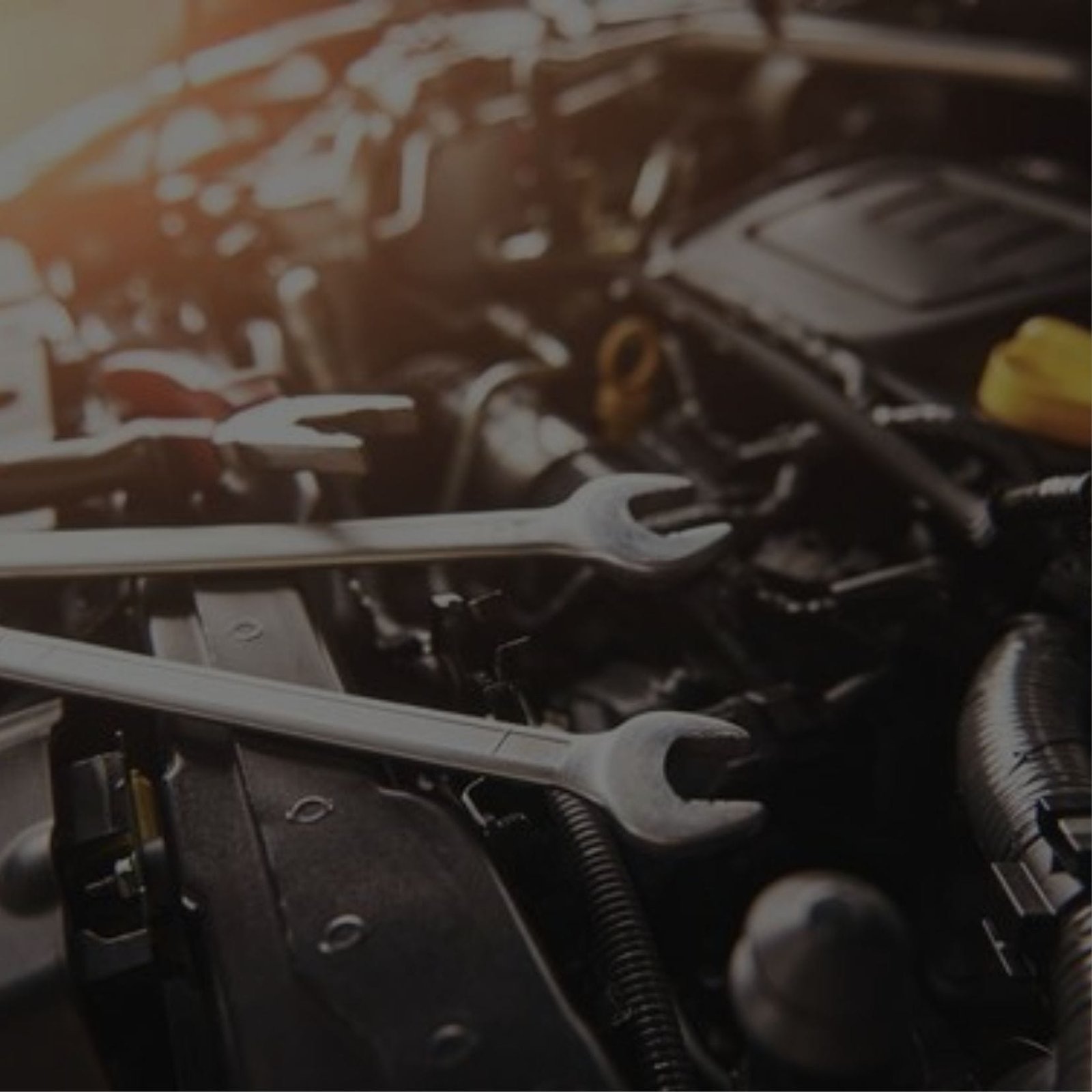 A close-up of a car engine with wrenches nearby