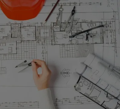 A person holding a construction plan and wearing a hard hat.