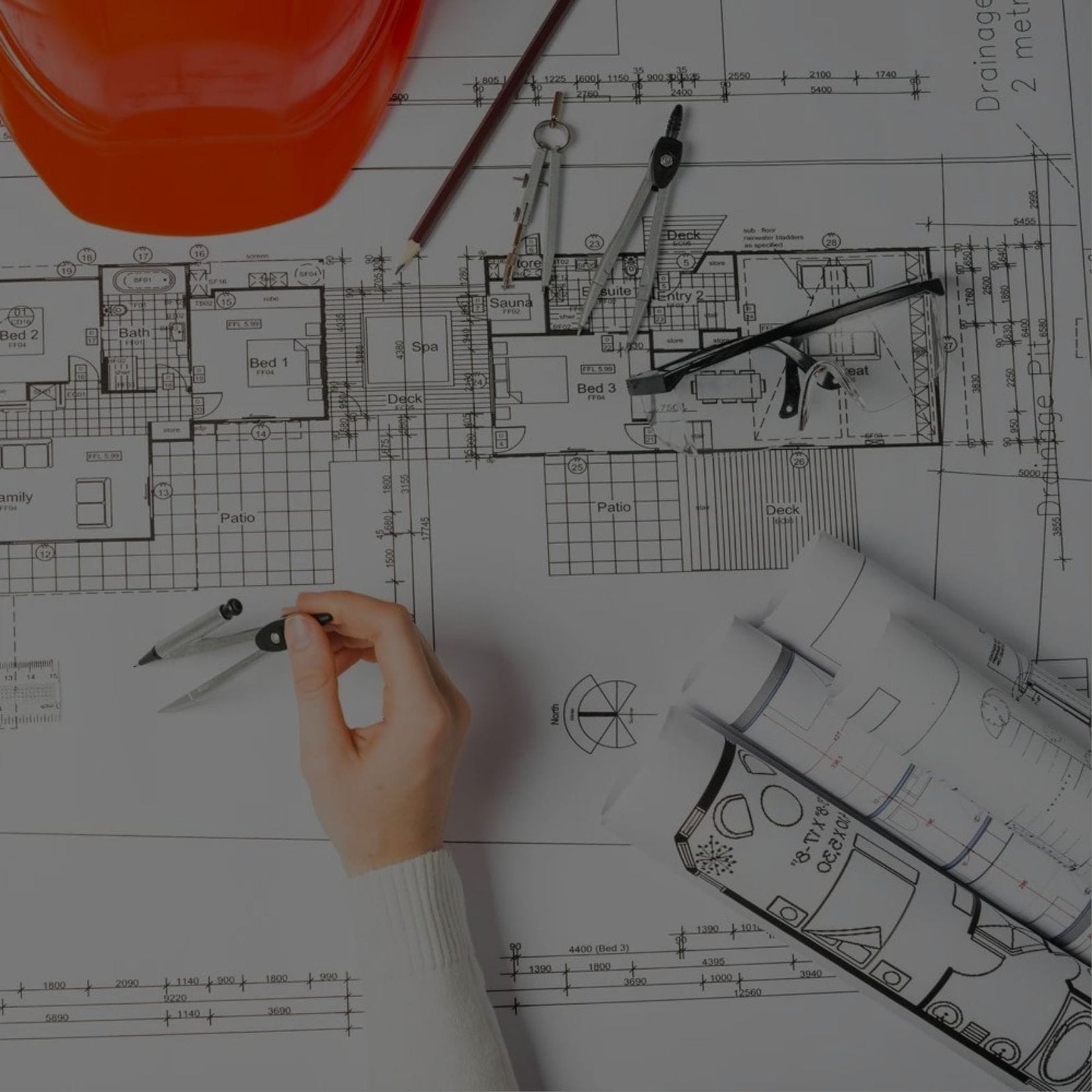 A person holding a construction plan and wearing a hard hat.