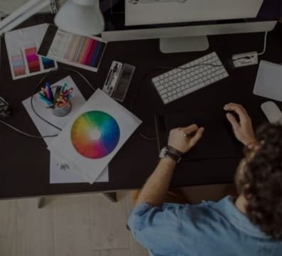 A designer working on a computer with a vibrant graphic