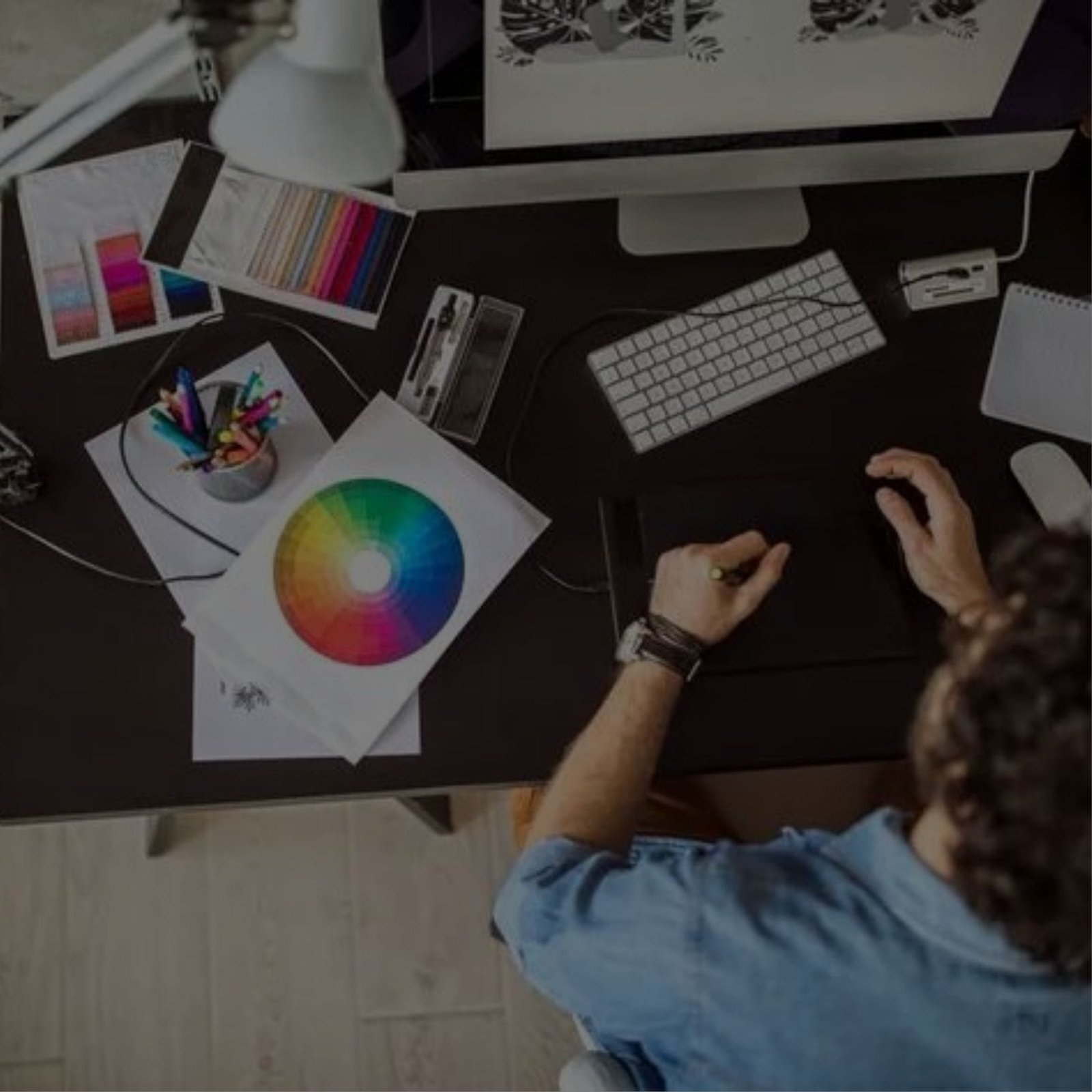 A designer working on a computer with a vibrant graphic
