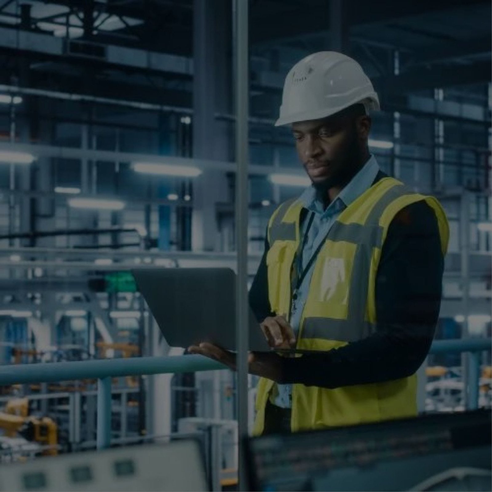 engineer in a hard hat and safety vest using a laptop to work on a project