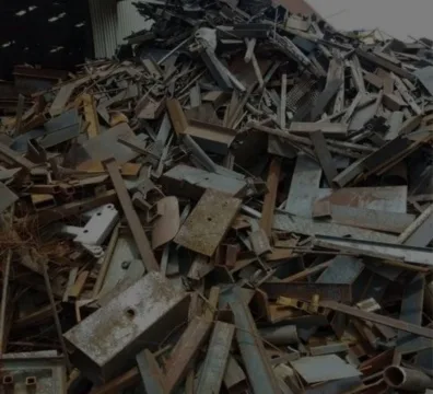 A pile of discarded Iron and Scrap Metal in front of a building.