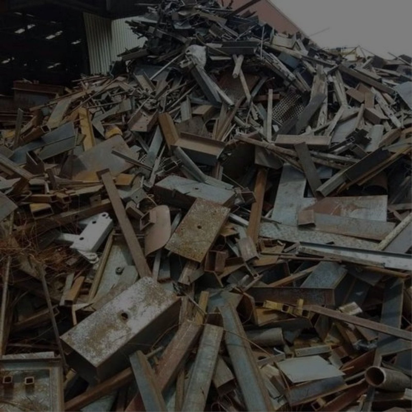 A pile of discarded Iron and Scrap Metal in front of a building.