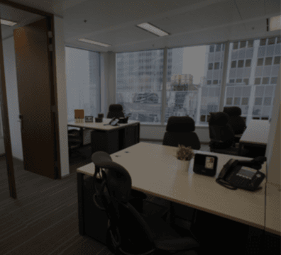 An Office Space Rental with a desk and chairs positioned in front of a window, providing a serene view.