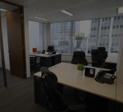 An Office Space Rental with a desk and chairs positioned in front of a window, providing a serene view.