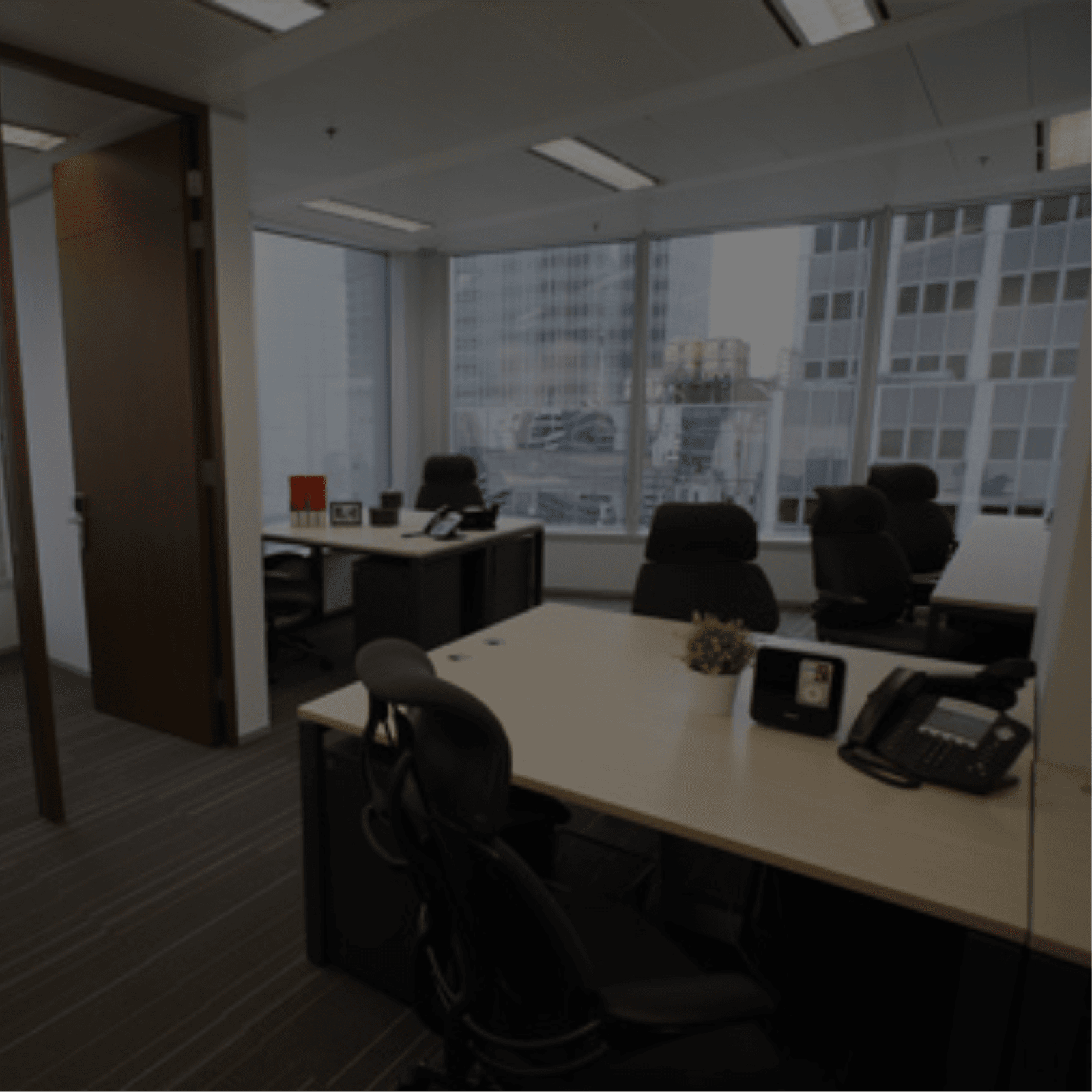 An Office Space Rental with a desk and chairs positioned in front of a window, providing a serene view.